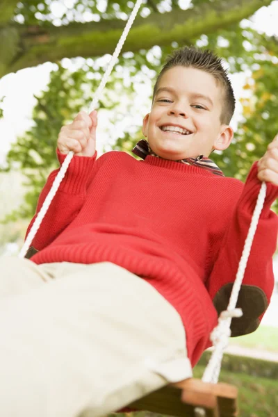 庭のブランコに乗って楽しんで若い男の子 — ストック写真