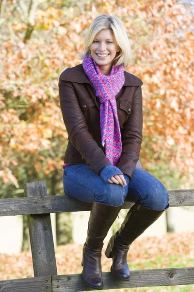 Jovem mulher sentada na cerca — Fotografia de Stock