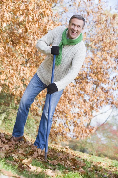 Homem sênior arrumando folhas no jardim — Fotografia de Stock