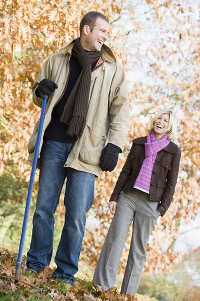 Casal raking up folhas de outono — Fotografia de Stock