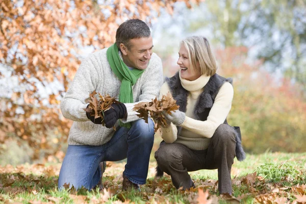 Pareja mayor recogiendo hojas de otoño — Foto de Stock