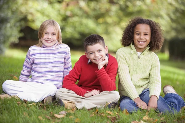 Група дітей, що сидять в саду — стокове фото