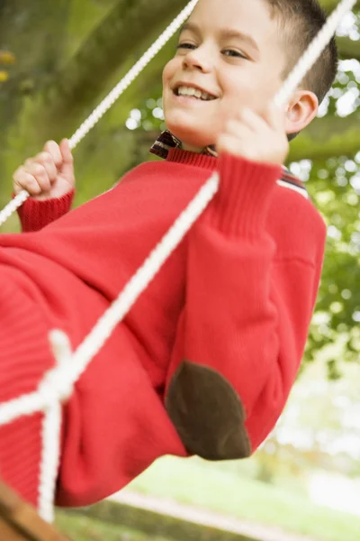 Jovem menino se divertindo no balanço — Fotografia de Stock