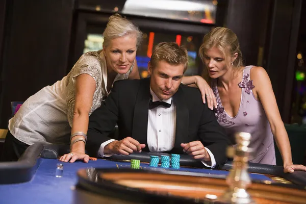 Man med glamorösa kvinnor i casino — Stockfoto