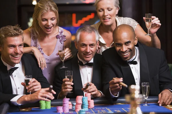 Grupo de amigos apostando en la mesa de ruleta — Foto de Stock