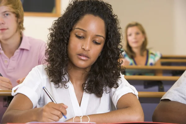 Kvinnliga collegestudent göra anteckningar under en föreläsning på universitetet — Stockfoto