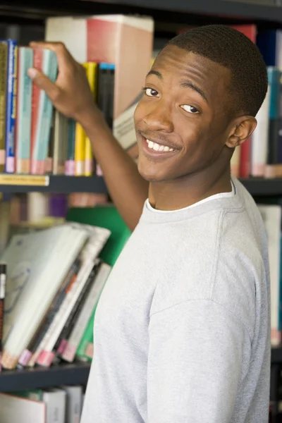 Estudante universitário do sexo masculino que procura um livro de biblioteca — Fotografia de Stock