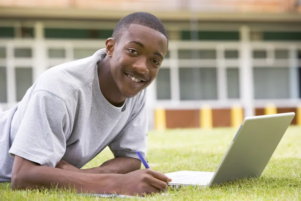 College student using laptop on campus lawn — Stock Photo, Image