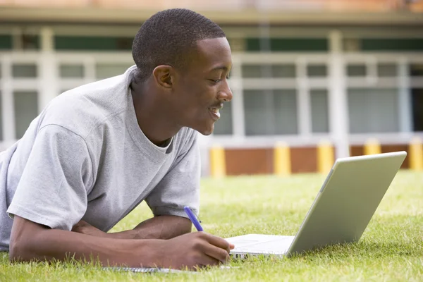 Étudiant utilisant un ordinateur portable sur la pelouse du campus — Photo