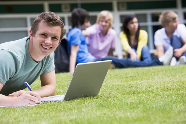 Νεαρός Άνδρας Χρησιμοποιώντας Φορητό Υπολογιστή Για Γκαζόν Πανεπιστημιούπολη Άλλους Φοιτητές — Φωτογραφία Αρχείου