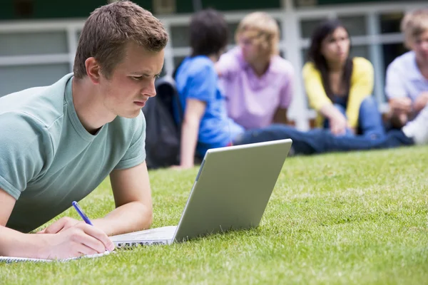 Young Man Using Laptop Campus Lawn Other Students Relax — Stock Photo, Image