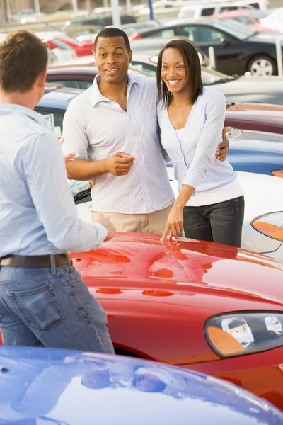 Młoda para dyskusji na temat nowego samochodu z sprzedawca — Zdjęcie stockowe
