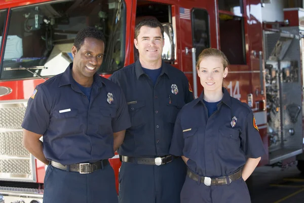 Портрет пожежників, що стоять біля пожежного двигуна — стокове фото