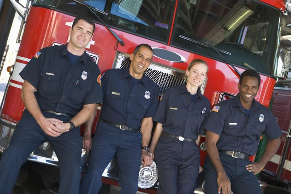 Портрет пожежників, що стоять біля пожежного двигуна — стокове фото