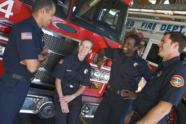 Firefighters chatting by a fire engine — Stock Photo, Image