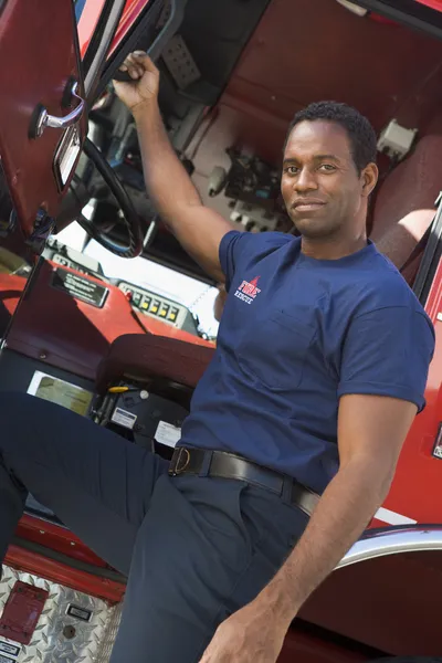 Пожежник стоїть біля кабіни пожежного двигуна — стокове фото