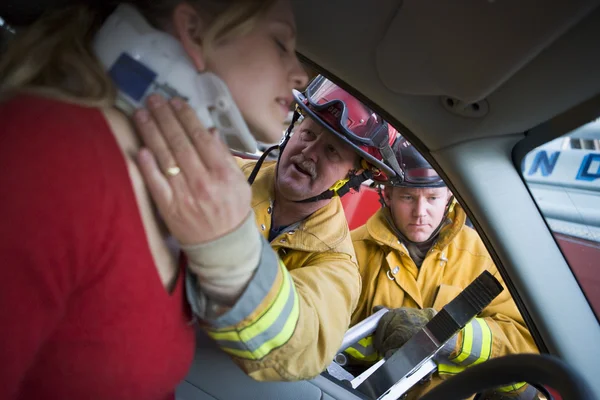 Vigili del fuoco che aiutano una donna ferita in macchina — Foto Stock