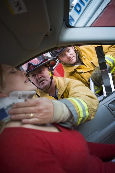 Firefighters helping an injured woman in a car — Stock Photo, Image
