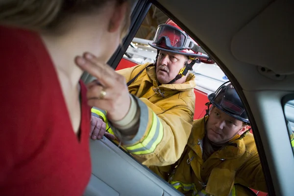 Пожежники допомагають пораненій жінці в машині — стокове фото