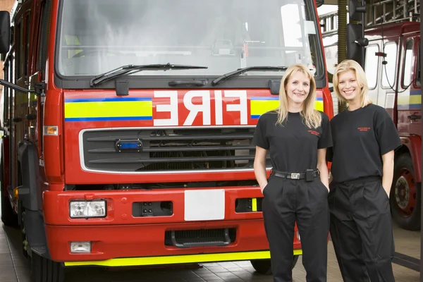 Портрет двух пожарных женщин, стоящих у пожарной машины — стоковое фото