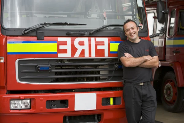 Porträt eines Feuerwehrmanns, der neben einem Feuerwehrauto steht — Stockfoto
