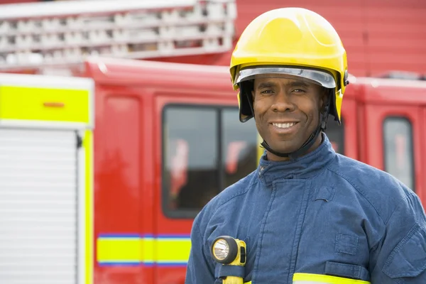 Portrait of a firefighter standing in front of a fire engine — Stock Photo, Image