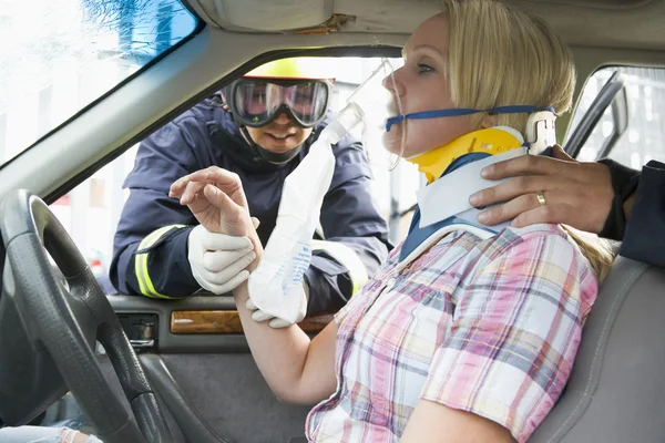 消防队员帮助受伤的女子在一辆车 — 图库照片