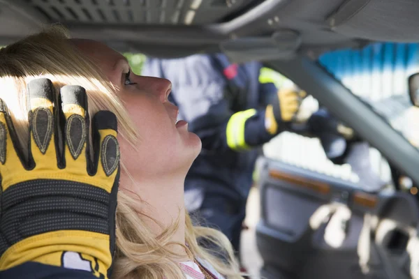 Пожарные помогают раненой женщине в машине — стоковое фото
