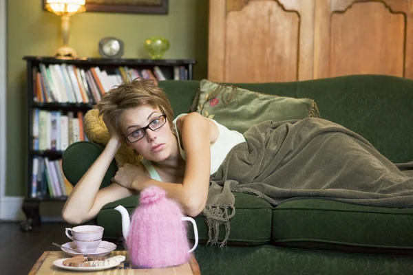 一个年轻的女人躺在她的沙发 — 图库照片