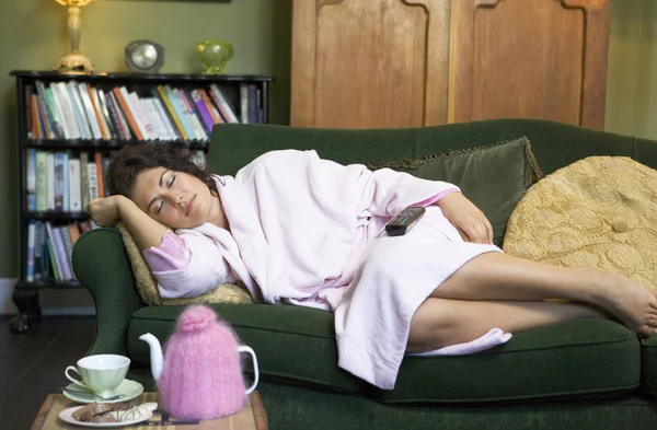 En ung kvinna liggande på hennes soffa med en tupplur — Stockfoto