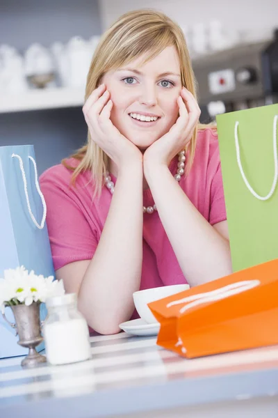 Shoping çanta ile bir kafede oturan genç bir kadın — Stok fotoğraf