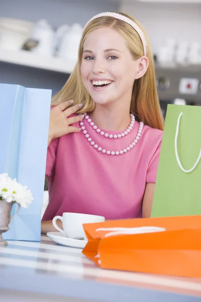 Uma jovem mulher sentada em um café com sacos de compras — Fotografia de Stock