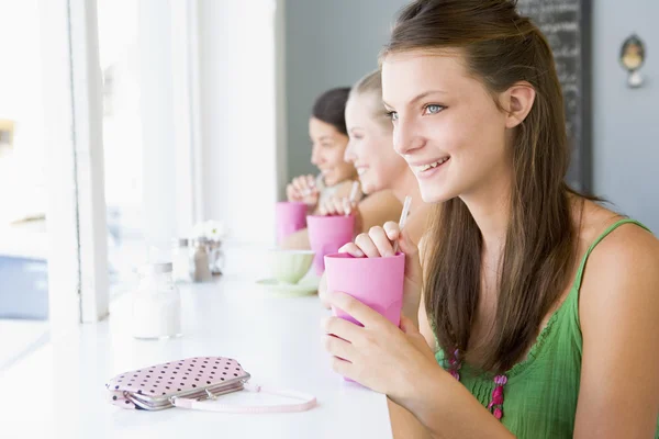 Молодая женщина пьет молочный коктейль в кафе — стоковое фото