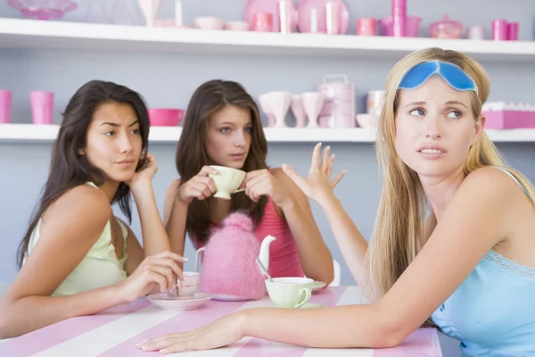 两个年轻妇女享受茶党 而一个坐分开磨合 — 图库照片