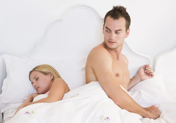 一对年轻夫妇和找担心的人在床上 — 图库照片