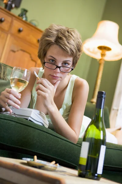 Μια νεαρή γυναίκα στο πιτζάμες της, πίνοντας κρασί και κάπνισμα — Φωτογραφία Αρχείου