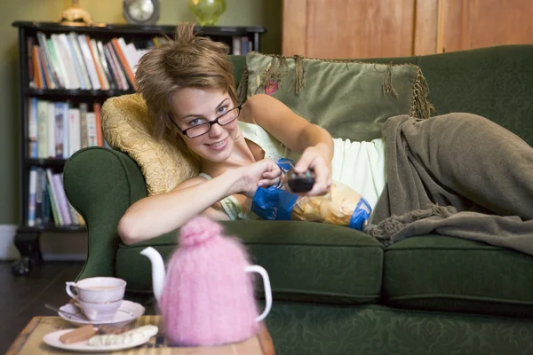 Молода жінка лежить на дивані дивитися телевізор — стокове фото