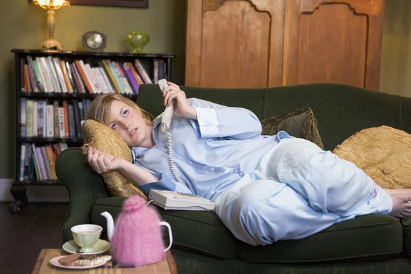 Mladá žena leží na jejím gauči mluví po telefonu — Stock fotografie