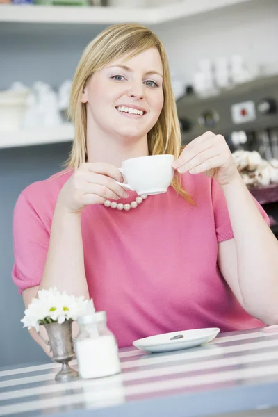 Młoda kobieta, siedząc w kawiarni picie herbaty — Zdjęcie stockowe