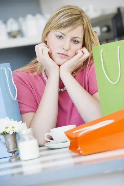A young woman sitting in a cafe with shopping bags — Stock Photo, Image