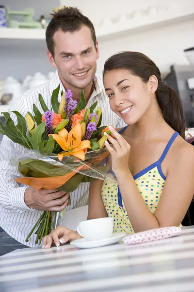 Młody Człowiek Daje Kwiaty Młodej Kobiety Kawiarni — Zdjęcie stockowe