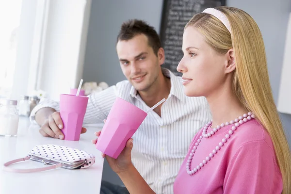 A young couple drinking milkshakes in a cafe — Stock Photo, Image
