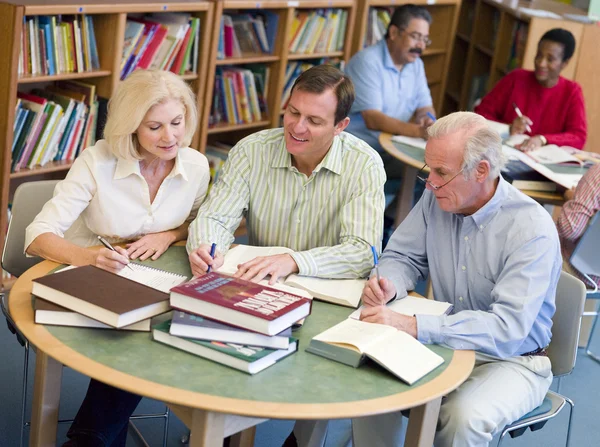 Зрелые студенты учатся вместе в библиотеке — стоковое фото