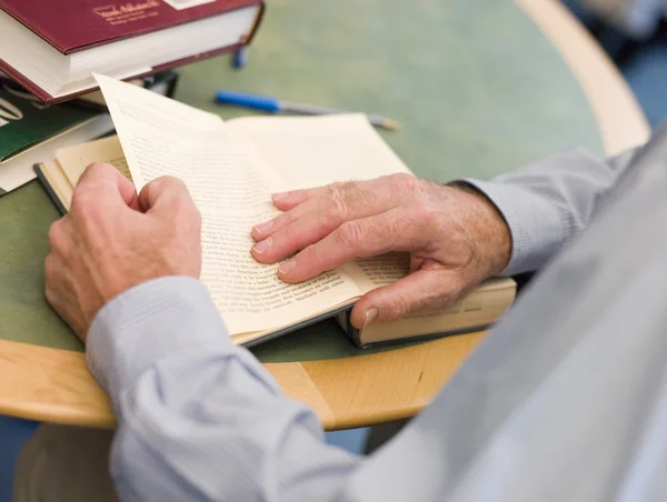 Close-up of mature student's hands turning book page in library — Stock Photo, Image