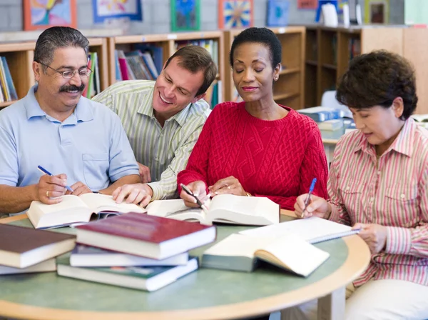 Lärare hjälpa mogna studenter i biblioteket — Stockfoto