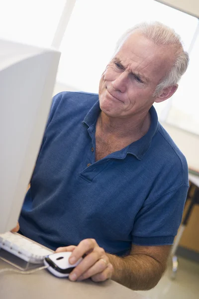 Ώριμος άνδρας των φοιτητών που frowning σε οθόνη υπολογιστή — Φωτογραφία Αρχείου