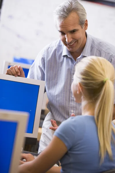 A teacher talks to a schoolgirl using a computer in a high schoo — Stock Photo, Image