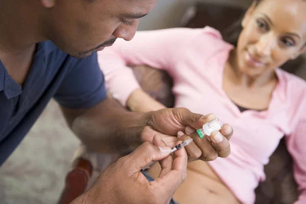 自宅で妊娠を達成するために薬物を注射する女性を助ける男 — ストック写真