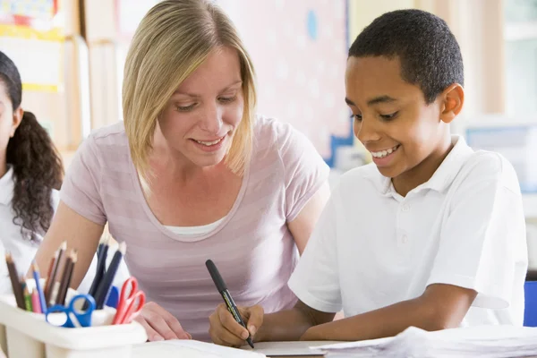 A schoolboy sitting with his teacher in class — Stock Photo, Image