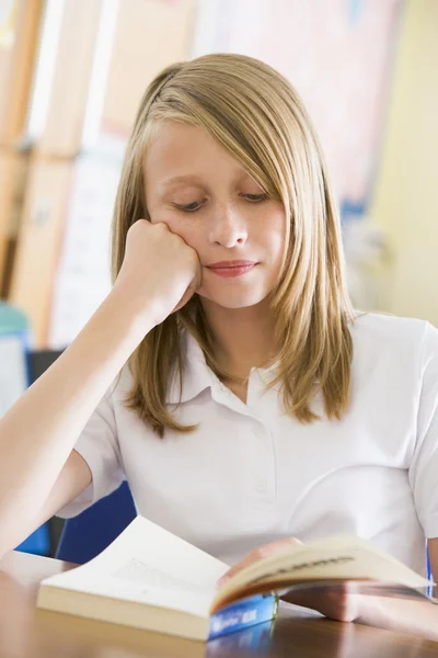 Schoolgirl reading a book in class — Stock Photo, Image